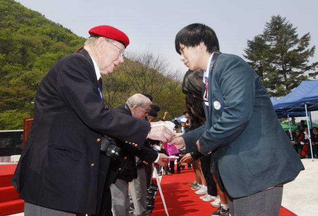 영연방 참전 노병들이 육군25사단장의 영접을 받으며 추모공원 준공 행사장에 입장한 뒤 국기에 대한 경례를 하고 경기지역 학생들에게 장학금을 전달하고 있다.