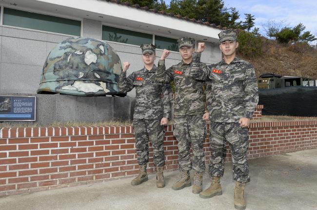 연평도 포격도발 당시 해병대의 불굴의 전투정신과 투혼을 보여 준 임준영 상병의 불탄 철모 조형물 앞에서 김성우·이원규·설정호 병장이 기념촬영을 하고 있다. 
부대 제공