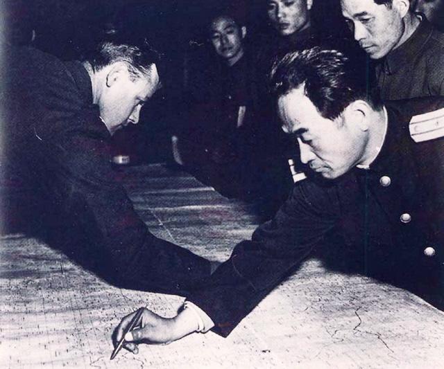 1951년 11월 26일 유엔군 연락장교 제임스 레이(왼쪽) 대령과 인민군 연락장교 장춘산이 판문점에서 휴전선을 정하는 협상을 시작하며 지도에 38선을 긋고 있다.  국방부 제공