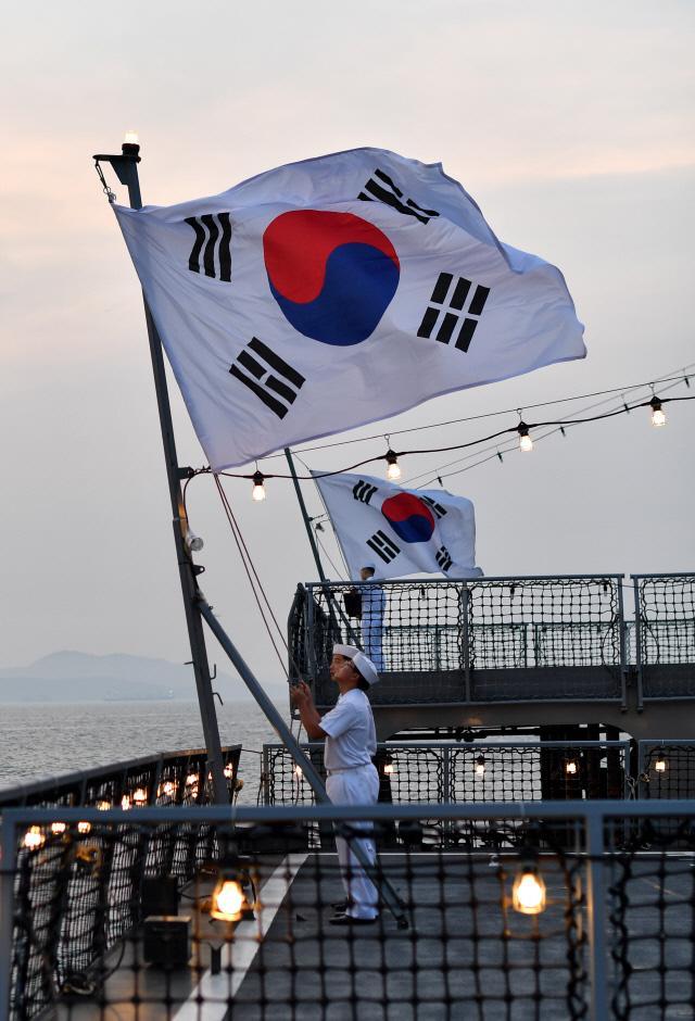 지난달 17일 일몰시각 태국 파타야 스리라차항에 정박 중인 강감찬함(앞쪽)과 군수지원함 화천함에서 각 배의 국기수들이 태극기 하강을 준비하고 있다.