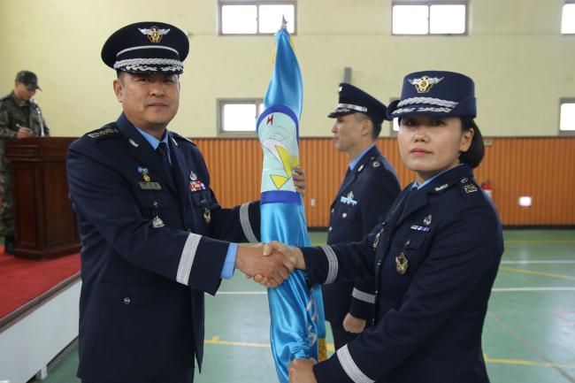공군관제사 7338부대 김종길(대령) 전대장이 15일 여군 최초 관제대대장으로 취임한 전수진(오른쪽) 소령에게 부대기를 전달하며 악수하고 있다.  부대 제공 