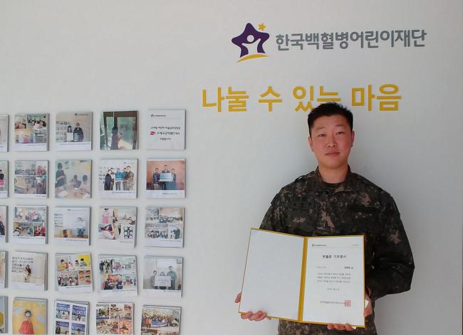 육군53사단 울산연대 김재엽 소령이 한국백혈병어린이재단에 10년간 모은 헌혈증 50장을 기부한 뒤 받은 기부증서를 들어보이고 있다.  부대 제공
