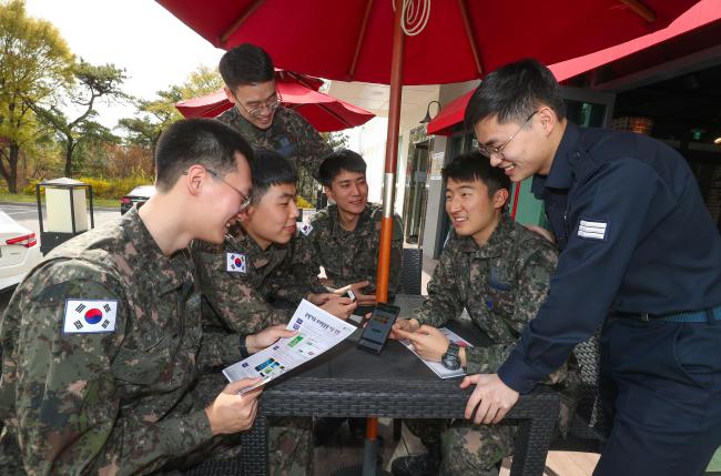 국군복지단에 근무하는 육·해·공군 병사들이 16일 일과를 마친 뒤 민영 콘도 이용을 신청할 수 있는 국군복지포털 애플리케이션의 ‘현역병 전용 예약’ 코너에 관해 대화를 나누고 있다.    이경원 기자