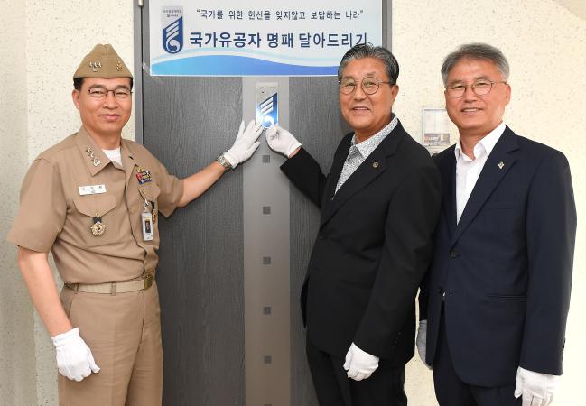 18일 해군교육사령부와 경남동부보훈지청 주관으로 열린 국가유공자 명패 달아드리기 행사에서 이성환(맨 왼쪽) 해군교육사령관과 안주생(맨 오른쪽) 경남동부보훈지청장이 김상길(가운데) 해군 예비역 대위의 자택을 찾아 명패를 달아드린 뒤 다 함께 기념사진을 찍고 있다.   사진 제공=박미현 중사(진)