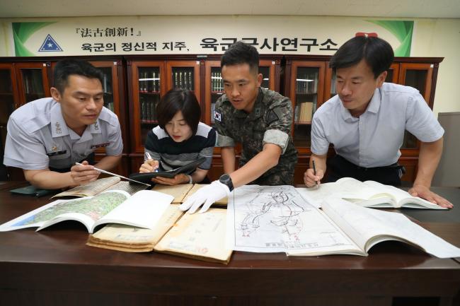 육군군사연구소 한국사전쟁연구장교 김영구(맨 왼쪽) 중령과 최홍기(오른쪽 둘째) 소령이 팀원들과 함께 전쟁사 연구를 위해 전쟁사료 및 수집자료를 살펴보고 있다. 