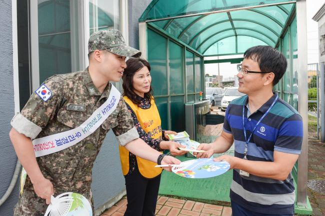 에너지 절약 캠페인에 나선 해군1함대 장병과 동해시청 공무원이 16일 부대 인근에서 출근하는 한 장병에게 에너지 절약 홍보물과 부채를 나눠주고 있다.   부대 제공