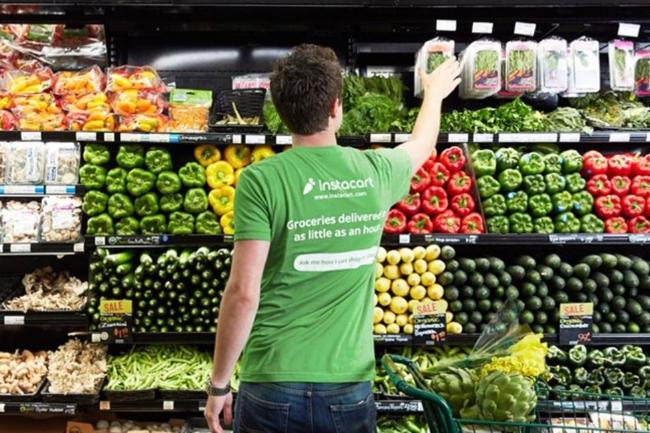 장 봐서   마트에서 장 보고 있는 인스타카트 쇼퍼. 티셔츠에는 ‘식료품은 가급적 1시간 안에 배달된다’라는 문구가 기재돼 있다.