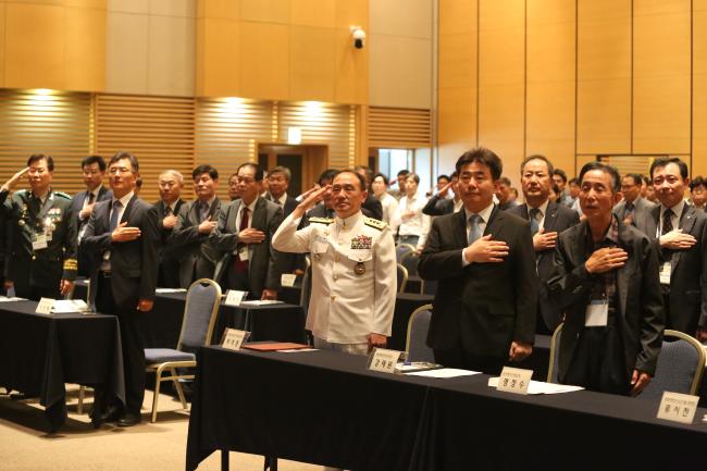 합참과 국방과학연구소, 한국전자파학회가 19일 대전컨벤션센터에서 개최한 ‘2019 전자전 워크숍 및 전시회’에서 참석자들이 국기에 대한 경례를 하고 있다.  합참 제공 