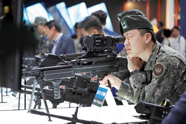 지난 15일 개막한 ‘서울 국제 항공우주 및 방위산업전시회(ADEX) 2019’가 19일부터 ‘일반 관람일’로 전환된다. 사진은 ADEX 행사장을 찾은 한 육군 장교가 K15 경기관총을 기반으로 제작한, 경량화된 7.62㎜ 기관총을 살펴보는 모습. 성남=조종원 기자