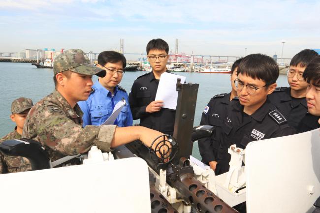 지난 18일 경기도 평택항 해경전용부두에서 해군2함대 고속정 무장부사관이 평택해양경찰서 함정 승조원들에게 50구경 중기관총 운용법을 교육하고 있다.   평택해양경찰서 제공