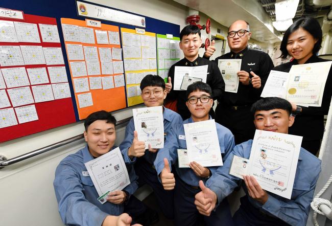 해군2함대 영주함 장병들이 함정 내부 벽에 걸린 만다라트 계획표 앞에서 올해 취득한 자격증을 들어 보이고 있다.   사진 제공=최호진 중사