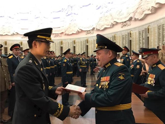 육군지상작전사령부 근무지원단 도영명(소령·왼쪽) 방공대장이 러시아 육군지휘참모대학장으로부터 최우수 졸업생에게 수여하는 ‘붉은 졸업장’을 받고 있다.  부대 제공