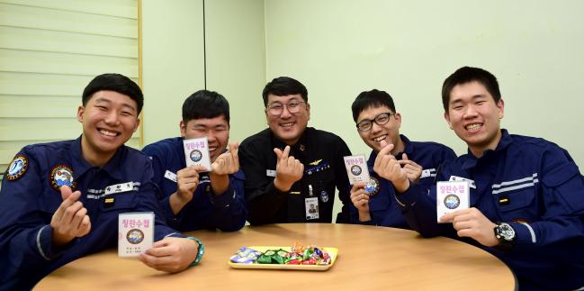 해군6항공전단 653정비대대 서근택(가운데) 주임원사가 부대 휴게실에서 영내병사들과 간담회 중 칭찬수첩을 들고 기념촬영하고 있다. 사진 제공=손정민 중사