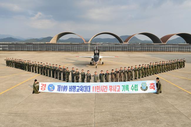 공군1전투비행단 장병들이 189비행교육대대의 11만 시간 무사고 비행 기록을 축하하는 기념사진을 찍고 있다. 
 부대 제공