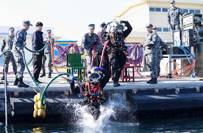 14일 동해군항에서 표면공급잠수체계(SSDS) 장비를 착용한 해군1함대 구조작전중대 장병과 동해해경 해양특수구조대원이 바다로 뛰어들고 있다.   사진 제공=강병천 중사