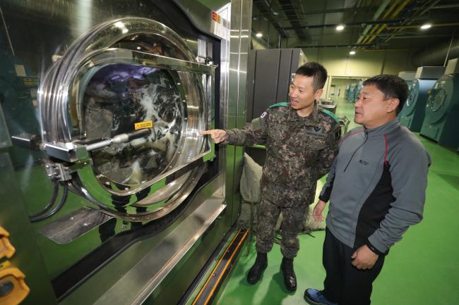 충남 논산 육군훈련소 크린센터에서 보급대장 현성민(왼쪽) 소령이 민간근로자와 함께 가동 중인 세탁기를 점검하고 있다.    사진=조종원 기자