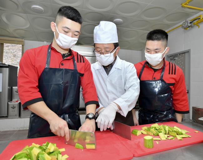 24일 해군군수사령부 보급창 영양 지킴이 이정준(가운데) 군무주무관이 진해 해군기지 내 해병대 신속기동부대 취사장에서 장병들에게 식재료 손질 방법을 설명하고 있다.   부대 제공