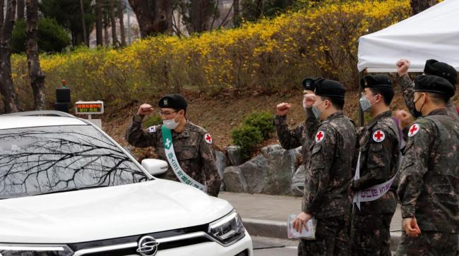 육군수도방위사령부 의무대 장병들이 영외에서 출근하는 간부들에게 ‘방패비타민 키트’를 증정하며 응원 메시지를 전하고 있다.  부대 제공