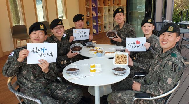 육군1군단 본부근무대 경비소대 소속 용사들이 배달 주문한 외부 음식을 먹기 전 밝은 얼굴로 대국민 응원 메시지를 전달하고 있다. 군단은 지역경제를 돕고자 연간 13억 여원의 장병 영외급식 예산을 이달 안에 모두 사용할 방침이다. 부대 제공
