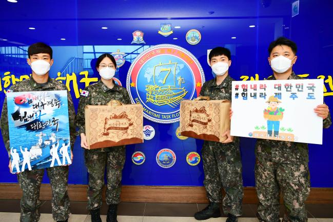 해군7기동전단 장병들이 제주지역 농가를 돕기 위해 구매한 농축산품을 들고 지역사회에 응원 메시지를 전하고 있다.  부대 제공.
