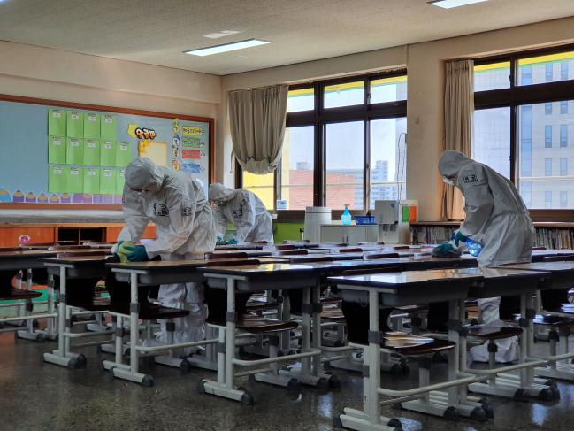 육군50사단 장병들이 6일 신종 코로나바이러스 감염증(코로나19) 확산 방지를 위해 개학을 미룬 대구 중구 계성초등학교 교실에서 방역작업을 하고 있다.    부대 제공