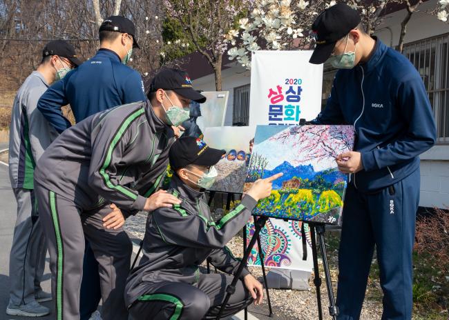 육군72사단이 최근 ‘봄’을 주제로 개최한 문화예술 공모전 ‘상상문화 올림픽’ 전시회에서 장병들이 따뜻한 봄 햇살을 즐기며 전시 작품을 감상하고 있다.  부대 제공 