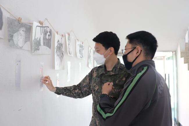 육군 50사단 화랑연대 장병들이 지난 15일 열린 동아리 성과발표회에서 드로잉동아리 회원들이 그린 그림 중 마음에 드는 작품에 투표하고 있다.  부대 제공