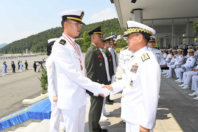 29일 해군사관학교 연병장에서 거행된 제128기 해군·해병대 학사사관 임관식에서 부석종(오른쪽) 해군참모총장이 우등상 수상자들에게 상장을 수여한 뒤 악수로 격려하고 있다.  해군 제공 