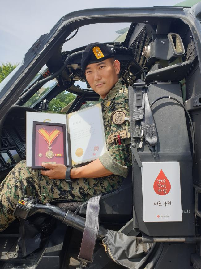 육군특수전사령부 특수작전항공단 폽핀스대대 임태수 준위가 헌혈유공장 명예대장을 들어 보이고 있다.  부대 제공
