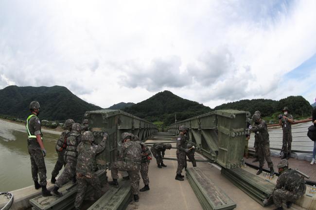 12일 육군3군단 공병여단 장병들이 최근 집중호우로 마을과 외부를 잇는 양지교 상판 일부가 내려앉으면서 고립된 지역 주민들을 위해 군 작전용 교량인 ‘간편조립교’를 구축하고 있다.  인제=조종원 기자