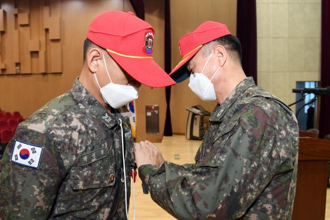 지난 22일 해군교육사령부에서 열린 훈련교관 교육과정 수료식에서 김영수(오른쪽) 기초군사교육단장이 제병지휘자 박성원 중사에게 훈련교관 휘장을 달아주고 있다.  해군 제공