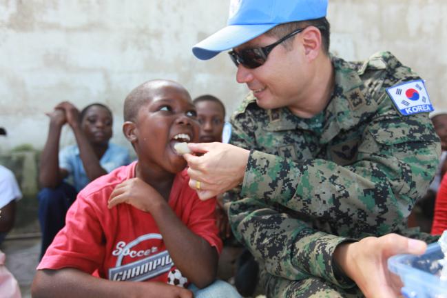 단비부대는 아이티 재건을 위한 유엔 평화유지활동에 참여해 공병·의무·민사 작전을 수행했다. 사진은 단비부대 장병이 2010년 당시 현지 아동시설에서 어린이들과 간식을 먹는 모습.  국방일보 DB