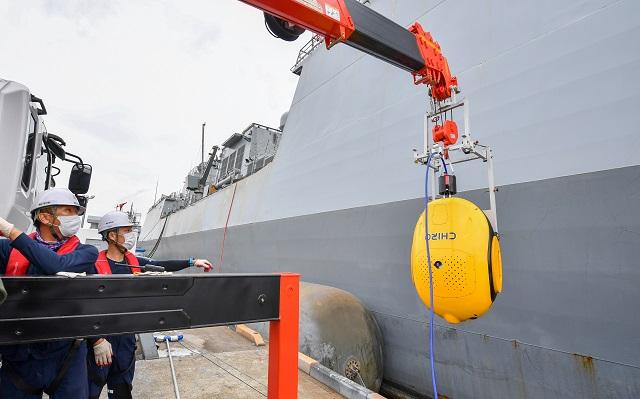해군군수사령부 정비창의 함정 정비 중 차량 크레인으로 노랑 색상의 수중 선체청소로봇 치로를 함정 측면에 부착시키는 장면. 사진 = 해군 정비창