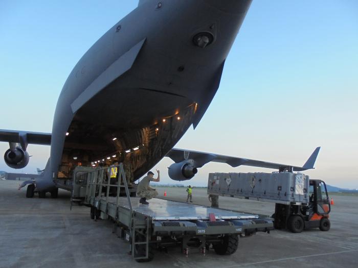 공군 김해기지에서 60수송전대 김해종합수송지원반 장병들이 카고로더와 지게차를 이용해 영국 공군 C-17 항공기에 화물을 적재하고 있다.  