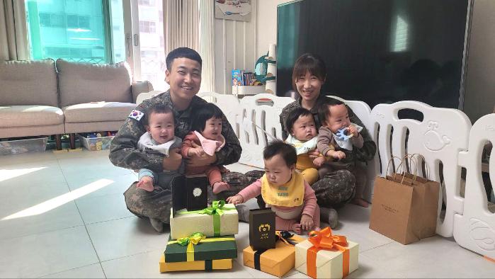 김진수 대위와 서혜정 대위, 다섯 쌍둥이가 김건희 여사의 첫 돌 축하 선물과 함께 기념촬영하고 있다. 대통령실은 김 여사가 축하 손편지와 원목 장난감 등의 선물을 보냈다고 12일 밝혔다. 대통령실 제공