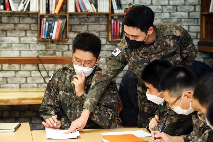 곽동현(오른쪽 위) 병장이 전우들의 영어 문제 풀이를 도와주고 있다.
