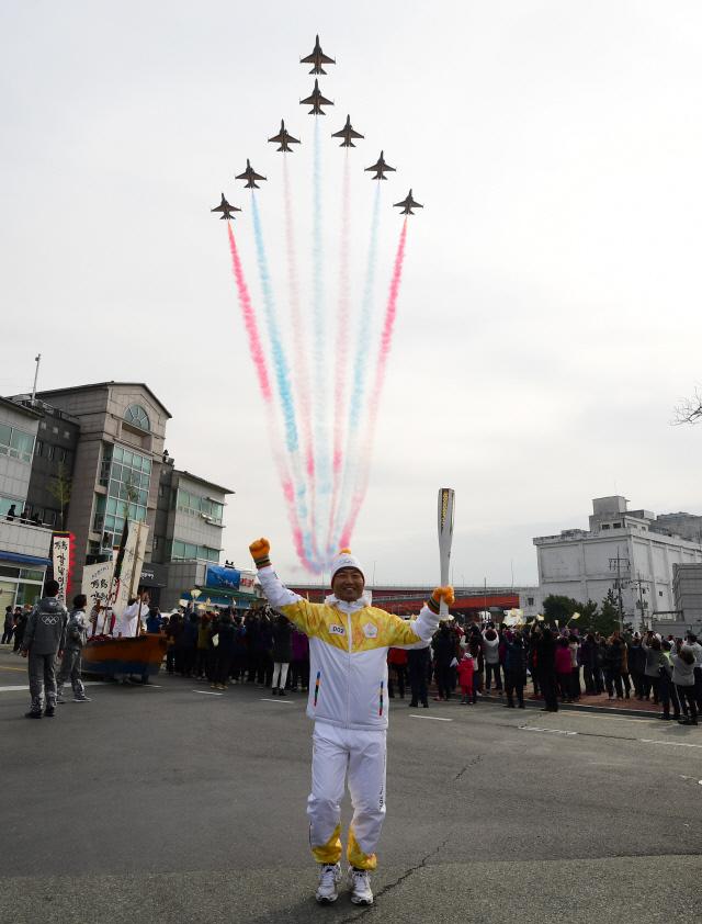 공군 특수비행팀 블랙이글스의 축하 비행이 하늘을 수놓는 가운데 2016년 탑건으로 선정된 공군11전투비행단 김학선 소령이 평창 동계올림픽 성화를 봉송하고 있다. 올림픽 성공 개최를 위해 투입된 9000여 명의 장병은 다양한 분야에서 지원활동을 펼치고 있다.   사천=조종원 기자