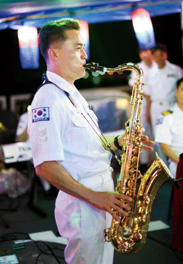 군악 부사관이 군사교류 활동의 하나로 열린 함상 리셉션에서 색소폰을 연주하고 있다.