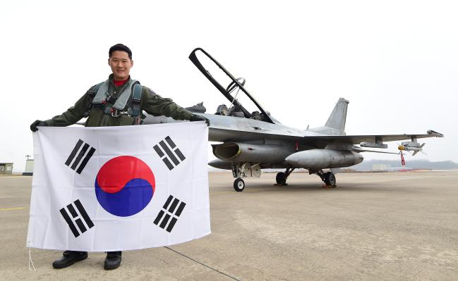 공군19전투비행단 소속 박병준 대위가 자신이 조종하는 F-16 전투기 앞에서 태극기를 펼쳐 보이고 있다.   충주=조종원 기자