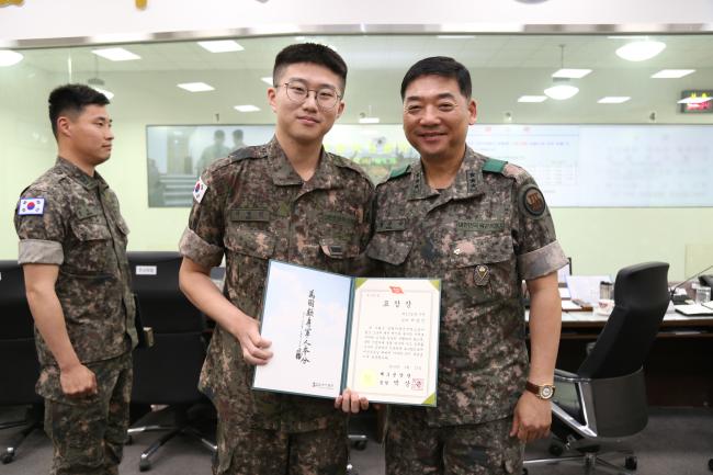 박상근(오른쪽) 3군단장이 자살징후를 보인 전우의 행동을 식별 및 보고해 극단적 선택을 막은 육군12사단 임상조대대 서영진 일병에게 표창을 수여한 뒤 기념사진을 찍고 있다.  부대 제공 