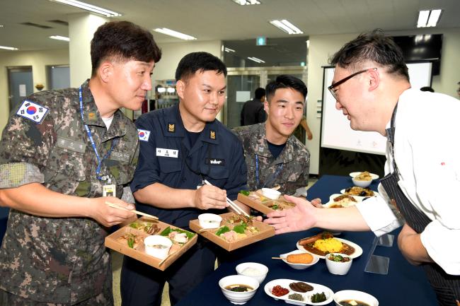 지난 26일 해군잠수함사령부 부사관식당에서 해군보급창과 CJ제일제당 주관으로 ‘잠수함 급식 개선 품평회’가 진행 중인 가운데 CJ조리팀장(맨 오른쪽)이 해군 급식관계관들에게 잠수함 맞춤형 메뉴를 설명하고 있다.   부대 제공