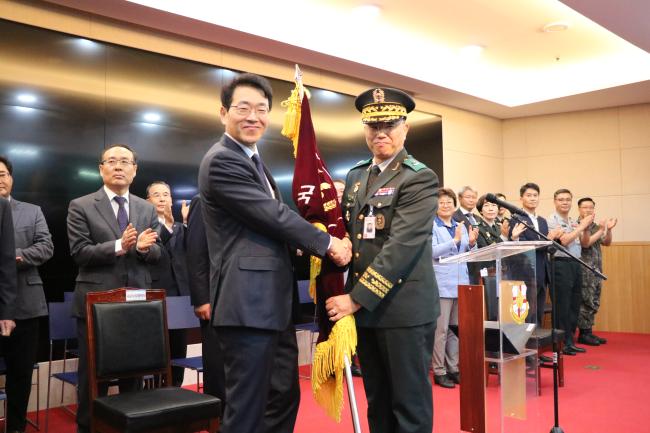 석웅(육군준장·오른쪽) 국군의무사령관이 1일 제26대 국군수도병원장으로 취임한 한호성 원장에게 부대기를 건네며 기념사진을 찍고 있다.   부대 제공