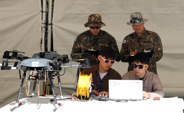 경연에 참가한 업체 관계자들이 드론을 조종하는 동안 대회 평가관들이 평가 기준을 확인하고 있다. 