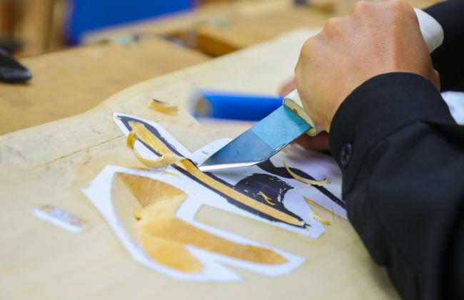 한 회원이 서각칼과 망치를 이용해 음각 기법으로 작품에 글자를 새기고 있다.