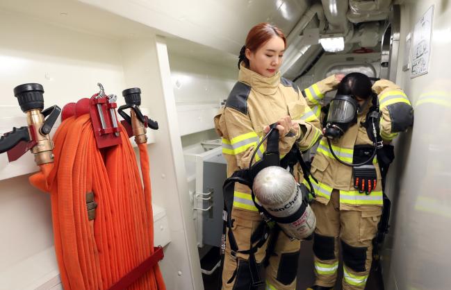 손상통제훈련 체험 중인 임 위원이 화재 현장으로 출동하기 위해 양압식공기실린더를 챙기고 있다. 