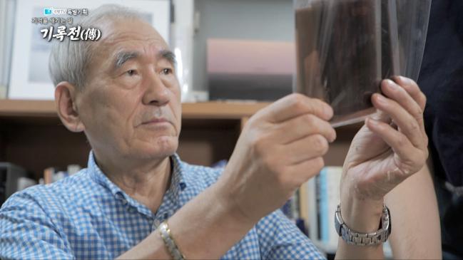 국방TV 특집 다큐멘터리 ‘기억을 새기는 일, 기록전(傳)’의 한 장면. 사진으로 6·25전쟁을 기록했던 국방부 소속 정훈국 임인식 사진대장의 아들 임정의 청암아카이브 소장이 아버지가 촬영한 6·25 당시 사진의 필름을 살펴보고 있다.