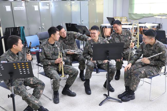 육군15사단 군악대 김형수(앞줄 오른쪽 둘째) 상병이 악기 연주를 마치고 전우들과 이야기 나누고 있다. 사단 군악대는 악기를 연주해야 하는 임무의 특성상 마스크를 계속 착용하기 어려운 만큼 군악대 장병들을 대상으로 연주 전후에 발열 체크를 실시하는 등 코로나19 방역지침을 준수한 가운데 연습·공연이 이뤄지도록 하고 있다.  부대 제공 