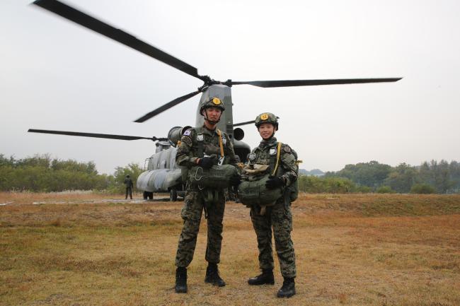 국제평화유지단 21대대 중대장 박민우(왼쪽) 대위와 특수전학교 학생지도부사관 임예원 중사가 지난 22일 동반 강하를 앞두고 항공기 앞에서 기념사진을 찍고 있다.  부대 제공