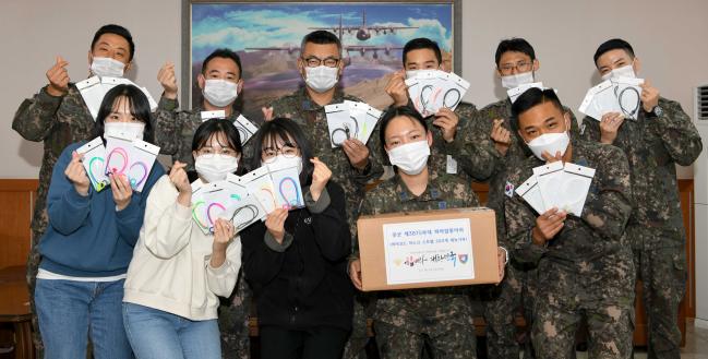 공군5공중기동비행단 동아리 ‘파라업(ParaUp)’ 회원들이 부대 인근 취약계층을 위해 사용이 어려운 낙하산 줄을 활용해 만든 마스크 스트랩을 들어 보이며 포즈를 취하고 있다. 뒷줄 왼쪽부터 최태환·이재영·정보경 상사, 엄성언 중사, 이수보 하사, 조상국 중사와 앞줄 왼쪽부터 이지은·이한빈·송지현 군무주무관, 전진희·이상훈 중사. 부대 제공  