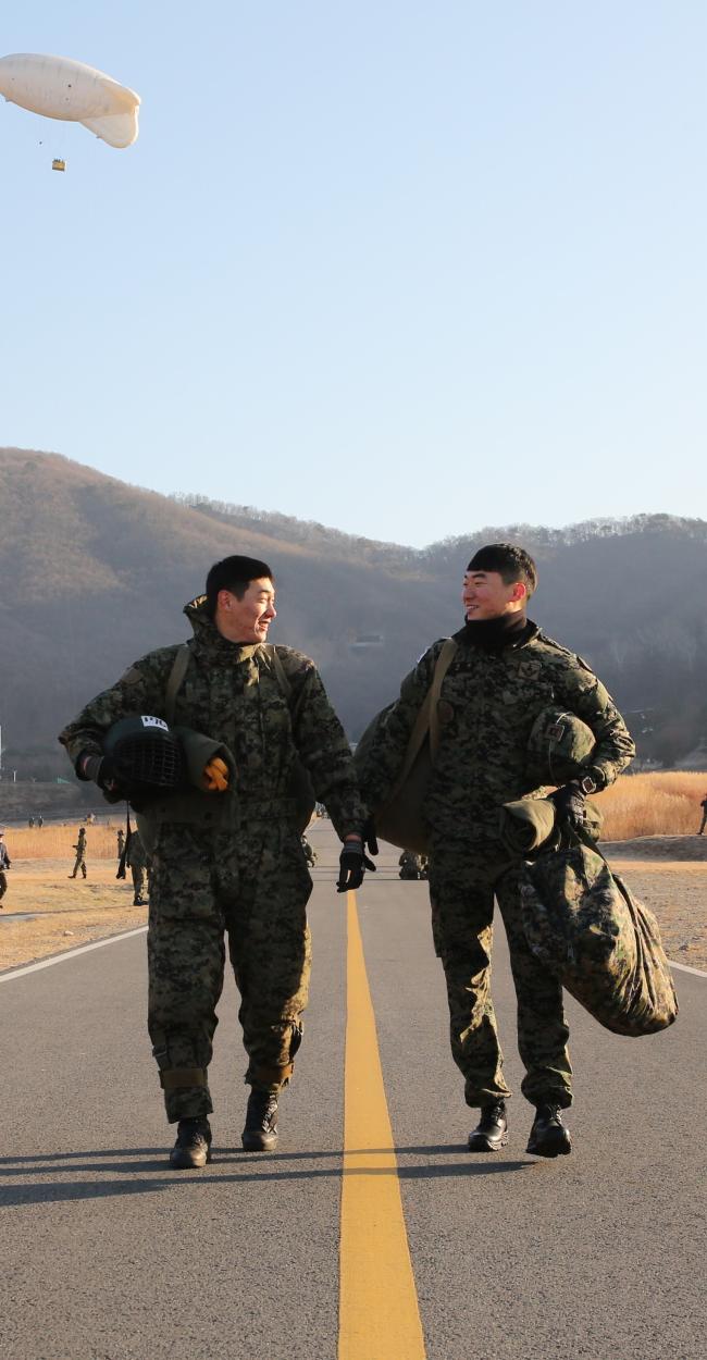 30일 육군특수전사령부 특수전학교 강하훈련장에서 ‘동반강하’를 마친 특전형제, 서성원(오른쪽) 하사와 서해원 상병이 동반강하의 감동을 나누며 집결지 방향으로 걸어오고 있다.  부대 제공